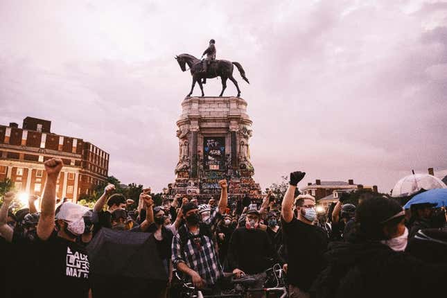 Protesters raise their fists in the air at the Robert E. Lee Statue on June 23, 2020 in Richmond, Virginia. While Virginia Governor Northam has ordered the statue to be taken down, a Richmond judge has issued an injunction temporarily blocking its removal. 
