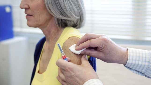 gray haired woman having her arm swabbed before a flu shot