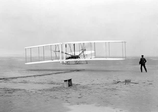 Orville Wright, lying at the controls on the lower wing, pilots the Wright Flyer on the first powered flight by a heavier-than-air aircraft, Dec. 17, 1903, at Kitty Hawk, N.C