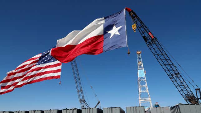 A Texas and American flag fly over oil trucks.
