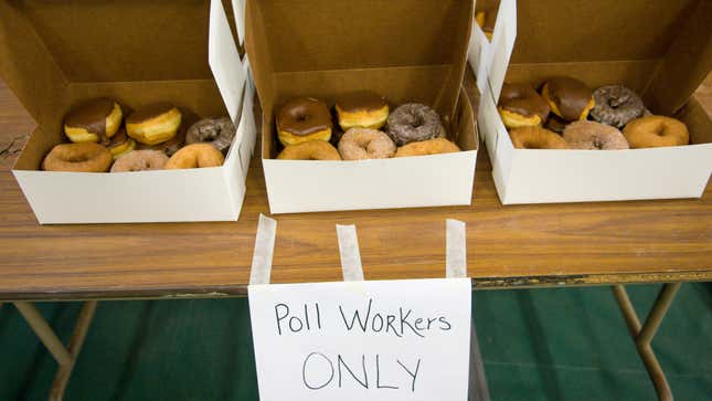 Table of donuts with sign labeled "poll workers only"