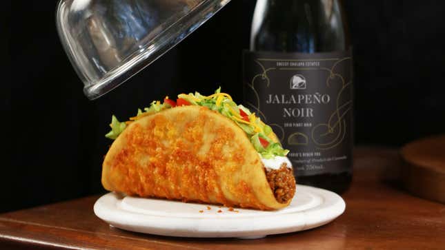 Taco Bell Chalupa on white plate atop wooden table with bottle of Taco Bell Jalapeno Noir on the side