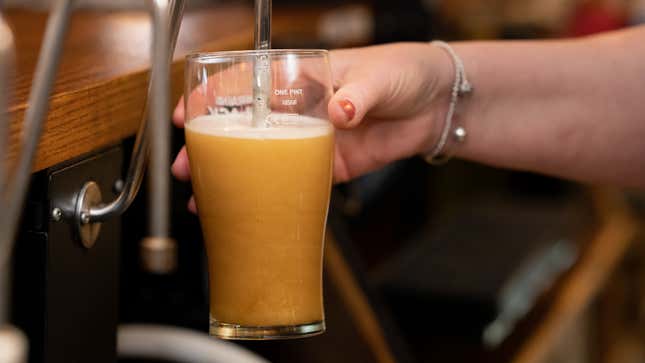 Woman pours pint of beer in pub