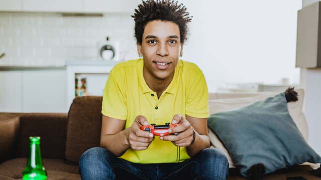 man playing video game on couch with beer