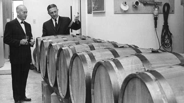 Tuxedos men stand over barrels of wine