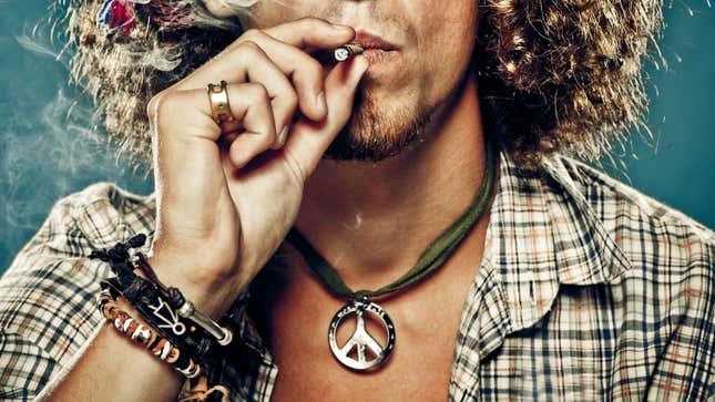 A man smoking a joint and wearing a peace sign necklace