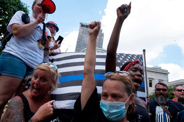Black Lives Matter protestors raise their fists in front of a “Blue Lives Matter” flag during an anti-mask right-wing protest “Stand For America Against Terrorists and Tyrants” at State Capitol on July 18, 2020 in Columbus, Ohio. 