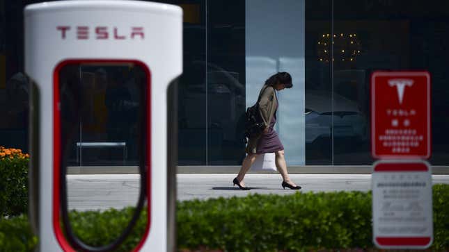 A woman walks past a Tesla car store in Beijing 