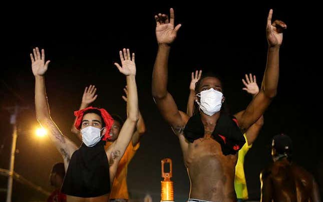  Demonstrators raise their arms and chant, “Hands up, Don’t Shoot”, as police clear them from the street as they protest the shooting death of Michael Brown on August 17, 2014 in Ferguson, Missouri.