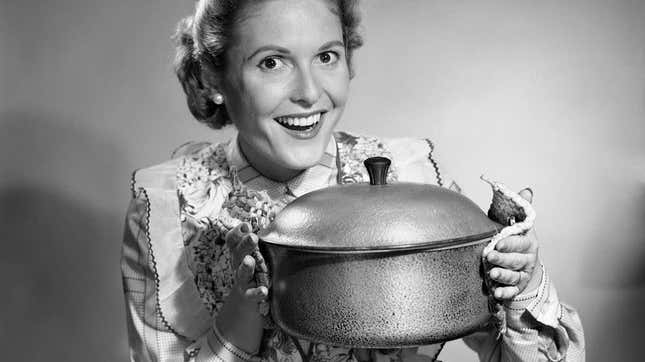 1950s housewife gleefully holds up Dutch oven