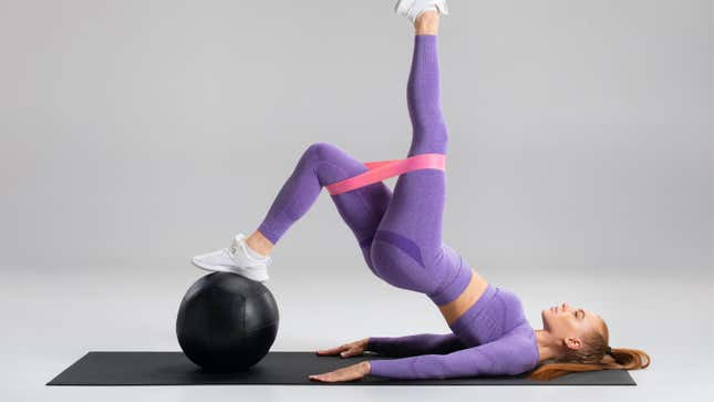 woman in purple doing a complex exercise with a booty band