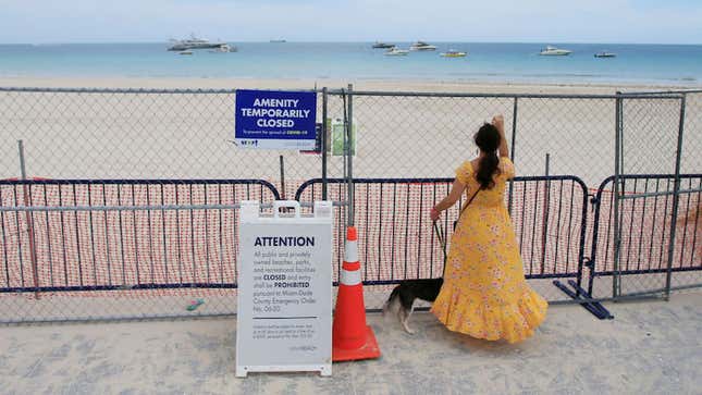 Miami Beach, Florida on July 4, 2020. A woman looks through the fence towards the beach. Miami-Dade County temporarily closed beaches over 4th of July weekend and imposed a curfew.