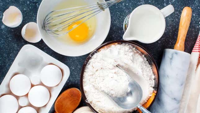 Spread of baking ingredients including eggs, flour, milk, and rolling pin