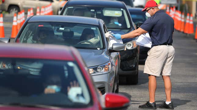 City of Hialeah employee Miguel Diaz hands out paper unemployment applications to people in their vehicles in front of the John F. Kennedy Library in Hialeah, FL. (April 8, 2020)