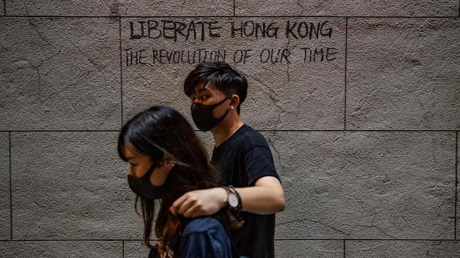 Protesters walk in front of graffiti during a rally in Chartered Garden on August 16, 2019 in Hong Kong