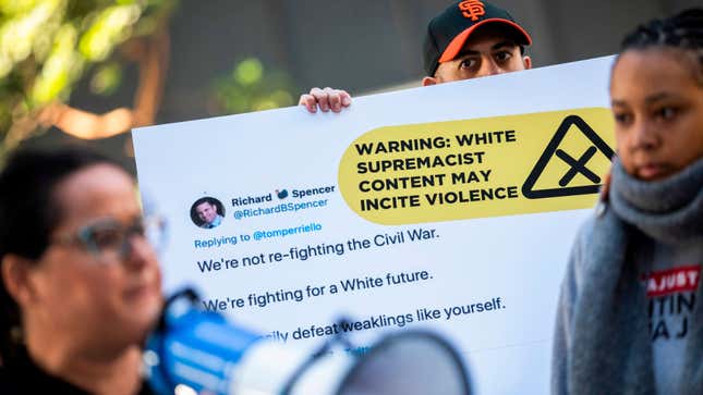 An activist holds a sign with an enlarged tweet while protesting with the activist group, Change the Terms Reducing Hate Online, outside Twitter Headquarters in San Francisco, California on November 19, 2019.