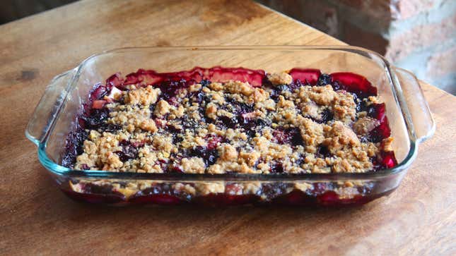 Pyrex baking dish full of fruit crumble on wooden tabletop