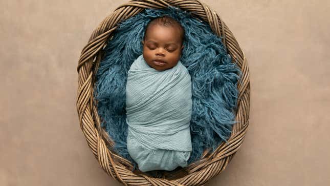 A sleeping, swaddled infant lies in a basket