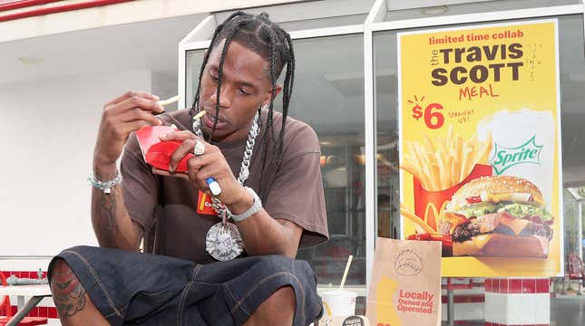 Travis Scott eating McDonald's fries in front of a sign advertising his new combo meal