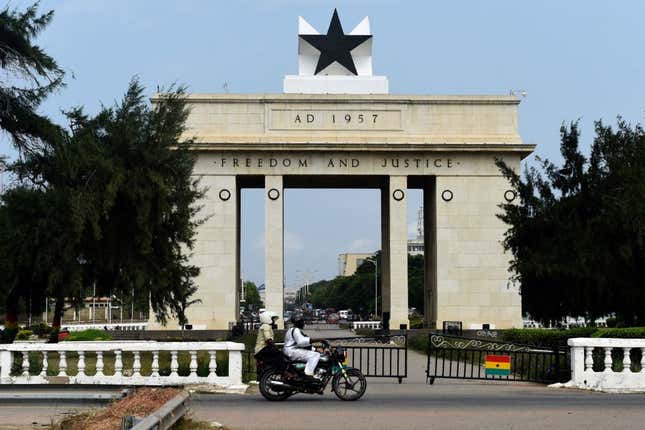 People on a motorcycle drive past the Black Star Gate in Accra, Ghana, on July 14, 2017.