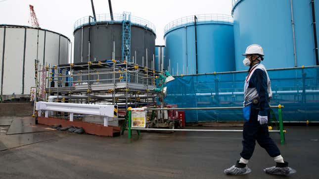 A person walks past storage tanks for contaminated water at the company’s Fukushima Daiichi Nuclear Power Plant
