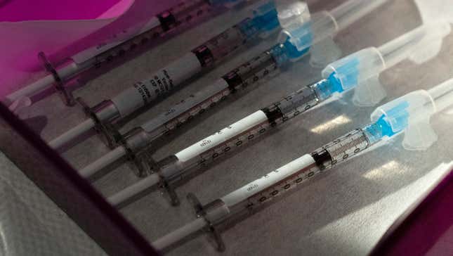 Five vaccine syringes on a tray