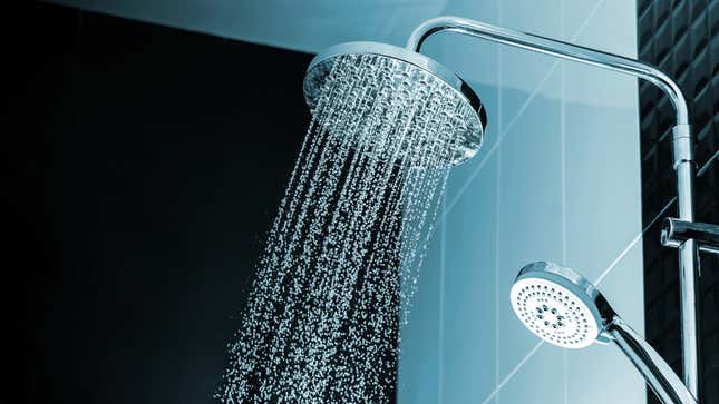 A round waterfall-style shower head sprays water in front of a light blue tiled wall. 