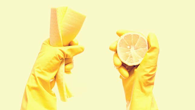 Hands clad in rubber gloves hold a towel and a whole lemon