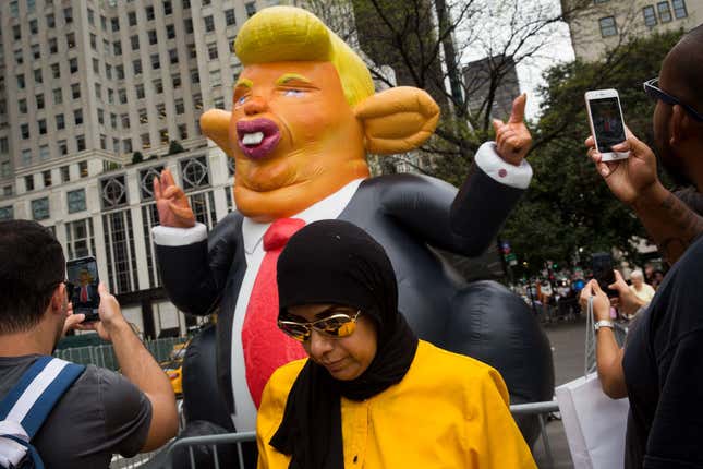 Pedestrians stop and take photos of a 15-foot tall inflatable rat in the likeness of U.S. President Donald Trump at the corner of Fifth Avenue and 59th Street up the road from Trump Tower, August 14, 2017 in New York City. 