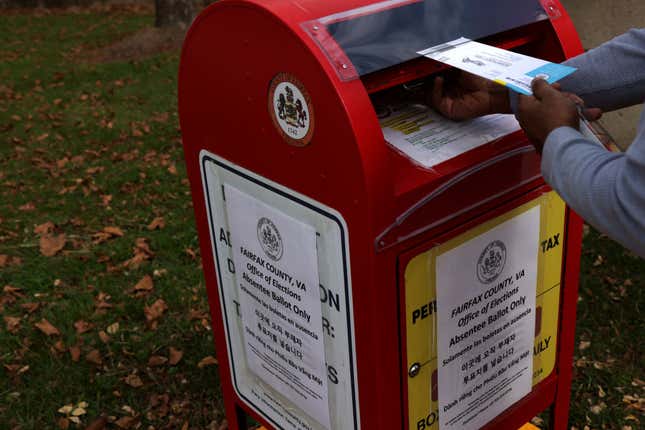 A voter drops off an absentee ballot for the November 3, 2020 elections into a collecting bin outside Fairfax County Government Center on October 19, 2020 in Fairfax, Virginia.