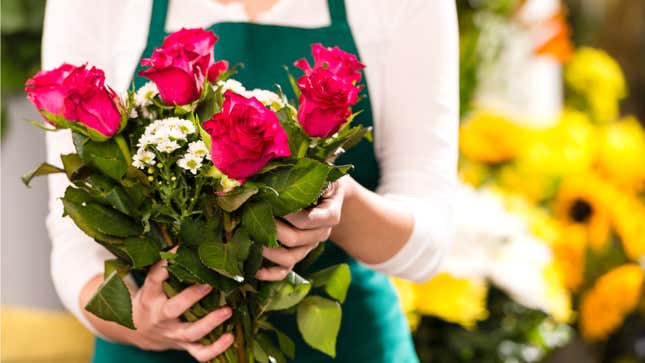 A woman in an apron holds a bouquet of flowers