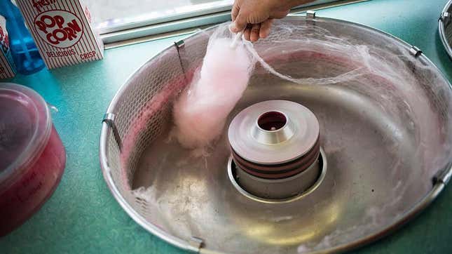 hand in cotton candy machine making candy