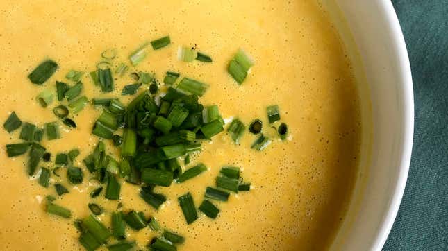 Bowl of pumpkin and spice soup topped with green onions