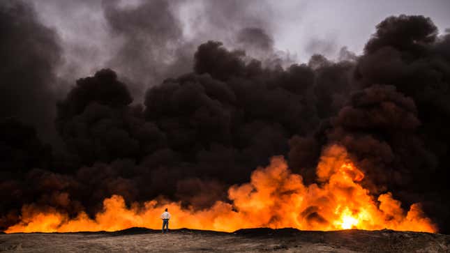 A man stands in front of a fire from oil that has been set ablaze in the Qayyarah area of Iraq.