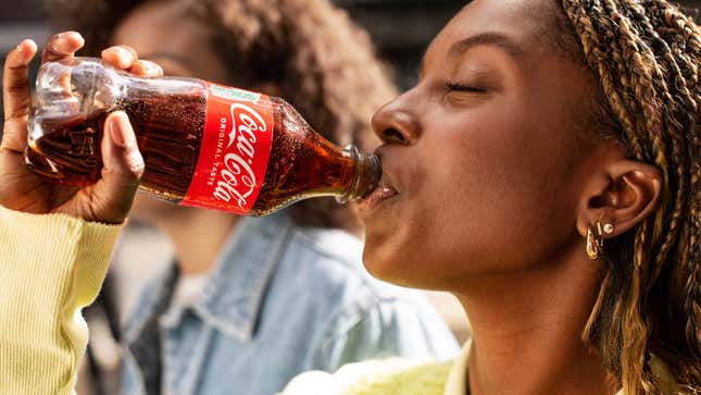 Person sipping from plastic Coca-Cola bottle [image provided by Coca-Cola]