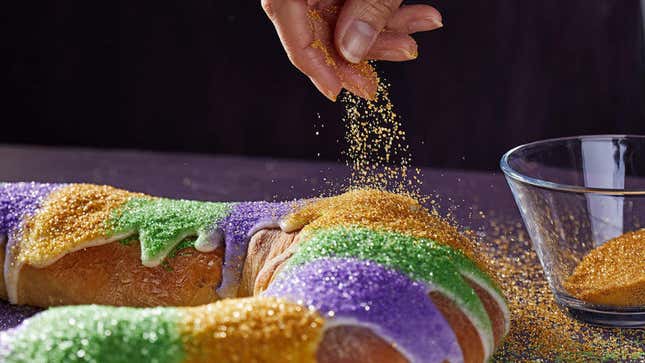 Hand sprinkling sugar onto king cake