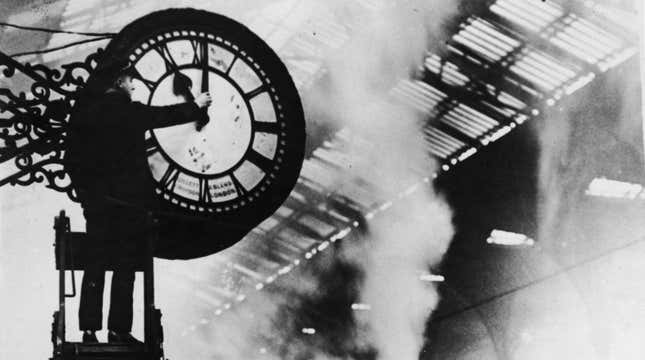 A man changes the time on an old-fashioned train station clock