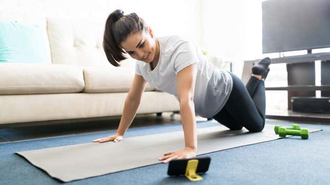 person exercising at home on a yoga mat with small dumbbells