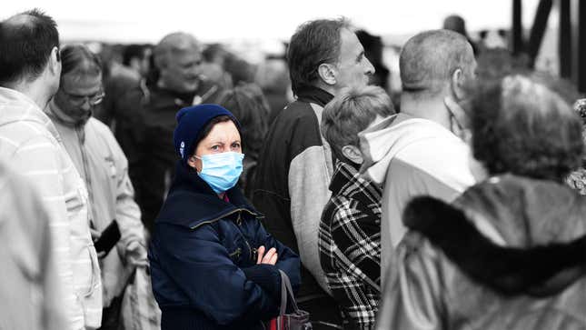 Woman with a mask is surrounded by unmasked people