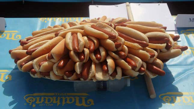 a large quantity of hot dogs piled on a table