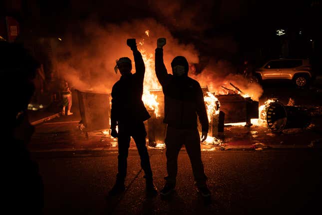 Demonstrators raise their fists as a fire burns in the street after clashes with law enforcement near the Seattle Police Departments East Precinct shortly after midnight on June 8, 2020, in Seattle, Washington.