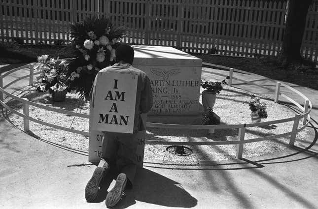 A striking Atlanta sanitation worker kneels at the grave of Dr. Martin Luther King Jr. after a rally by Southern Christian Leadership Conference supporting the strike in Atlanta on April 4, 1970. King was killed in Memphis, Tenn., two years earlier while supporting a sanitation workers’ strike there. The picket signs reading “I Am A Man” were first used in the Memphis strike. 
