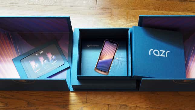 A picture of an overly constructed blue box with the label "razer." A phone, that is clearly a render, is set in the center of the box. The box lies on a wood floor.