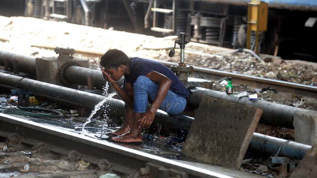 A man washes himself at a water pipe to cool down along the railway tracks in New Delhi.