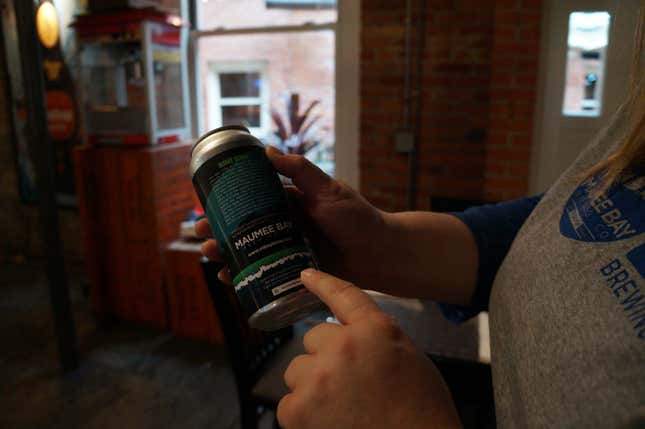 Shannon Mohr showing off the goods. The beer cans include information on the lake’s algae blooms.