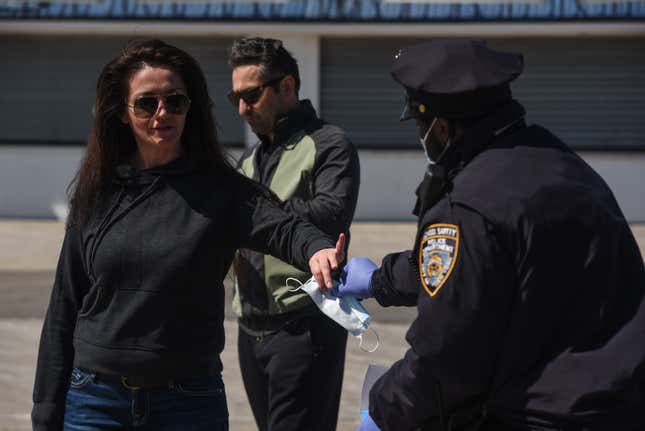 A person receives a protective mask from a member of the New York City police department on May 13, 2020 in the Brooklyn borough in New York City.