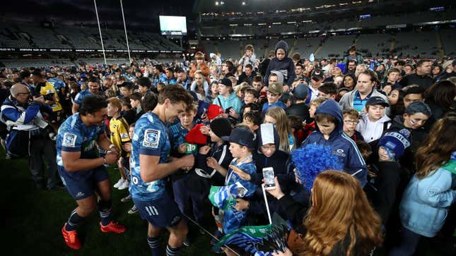 Life returns to normal in New Zealand without need for social distancing, as a crowd comes onto the field to get player autographs during round 1 of the Super Rugby Aotearoa match between the Blues and the Hurricanes at Eden Park on June 14, 2020 in Auckland, New Zealand. 