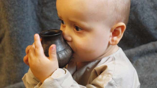 An infant drinks from a reconstructed feeding vessel similar to the ones analyzed in the new study.