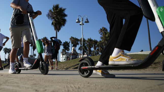 People ride Lime shared dockless electric scooters along Venice Beach on August 13, 2018 in Los Angeles, California.
