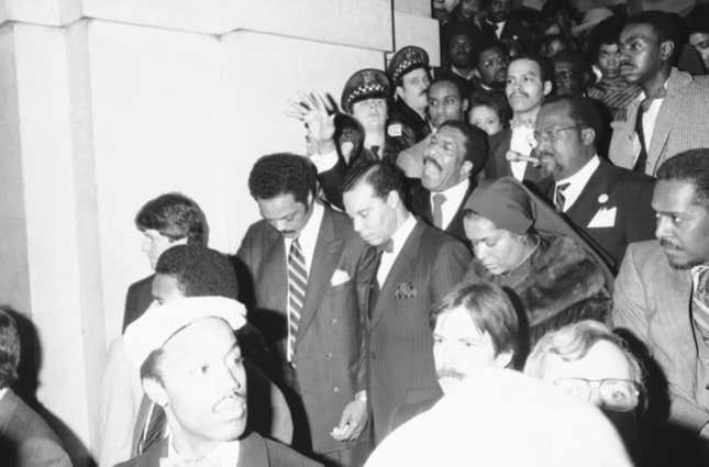 Democratic presidential hopeful Jesse Jackson, left, Louis Farrakhan,  center, head of the Nation of Islam, and his wife, Betsy Farrakhan, bow  their heads as the Rev. Clay Evans, behind Farrakhan, leads a prayer at  Chicago’s City Hall on Feb. 9, 1984, Chicago, Ill. Jackson  accompanied the religious leader as he registered to vote for the first  time in his life.